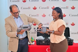 Head of Development Cooperation for Jamaica and Belize at the High Commission of Canada in Kingston, Shehryar Sarwar, explains features of a drone to Principal Director, National Spatial Data Management Branch (NSDMB), Ministry of Economic Growth and Job Creation, Alicia Edwards, during Monday’s (August 25) handover of several of the devices that have been provided under the Natural Resources Canada – Technical Assistance Partnership (TAP) Project. The presentation was made at the High Commission.
