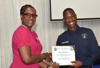 Permanent Secretary in the Ministry of National Security, Ambassador Alison Stone Roofe, presents a certificate to District Constable Ackeem Brown for successfully completing a six-week training course developed by the Jamaica Constabulary Force’s (JCF) Protective Services Division for district constables, during Friday’s (August 22) graduation ceremony at the Police Officer’s Club in Kingston.