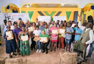 Land titles were distributed to these residents of Norwood in St. James, on August 11. With them are Prime Minister, Dr. the Most Hon. Andrew Holness (sixth left, back row), and Minister of National Security and Member of Parliament for the area, Hon. Dr. Horace Chang (sixth left, second row).