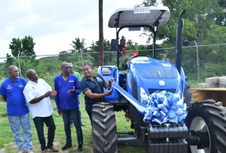 Minister of Agriculture, Fisheries and Mining, Hon. Floyd Green (right), cuts the ribbon to officially hand over a tractor to the National Irrigation Commission’s  (NIC) Hounslow office in Watchwell, St. Elizabeth on Friday (Aug. 15). Looking on (from left) are the NIC’s Director of Engineering and Technical Services, Rohan Stewart; Permanent Secretary in the Agriculture Ministry, Dermon Spence; and Chief Executive Officer at the NIC, Joseph Gyles.