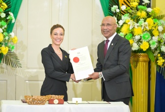 Governor-General, His Excellency the Most Hon. Sir Patrick Allen, presents the Instrument of Appointment to 
Minister of Foreign Affairs and Foreign Trade, Senator the Hon. Kamina Johnson Smith (left), during the swearing-in ceremony for Cabinet Ministers at King’s House on September 17.
