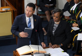 Senator Christian Tavares-Finson takes the Oath of Allegiance, during the swearing-in of members of the Upper House at Gordon House on Thursday (September 18). Observing is Clerk to the Houses of Parliament, Colleen Lowe.
