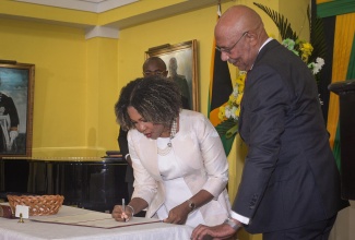 Governor-General, His Excellency the Most Hon. Sir Patrick Allen (right), observes as Minister of Education, Skills, Youth, and Information, Senator Dr. the Hon. Dana Morris Dixon, signs her Instrument of Appointment as a Minister, during a swearing-in ceremony for Ministers, held at King’s House in St. Andrew, yesterday (September 17).

