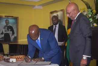 Governor-General, His Excellency the Most Hon. Sir Patrick Allen, looks on as the Minister of Labour and Social Security, Hon. Pearnel Charles Jr., signs the Instrument of Appointment during the swearing-in ceremony for 18 Cabinet Ministers at King’s House on Wednesday (September 17).

