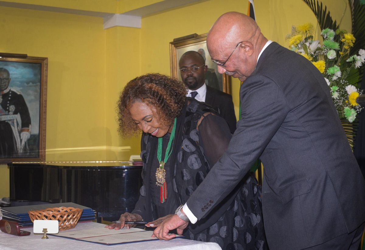 Governor-General, His Excellency the Most Hon. Sir Patrick Allen (right), guides Minister of Culture, Gender, Entertainment and Sport, Hon. Olivia Grange, as she signs the Instrument of Appointment during Wednesday’s (September 17) Swearing-in Ceremony for Cabinet Ministers at King’s House.
