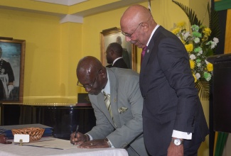 Governor-General, His Excellency the Most Hon. Sir Patrick Allen (right), observes as Minister of Local Government and Rural Development, Hon. Desmond McKenzie, signs the Instrument of Appointment during the swearing-in of Cabinet members, held at King’s House in St. Andrew on Wednesday (September 17).