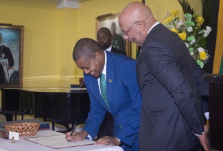 Governor-General, His Excellency the Most Hon. Sir Patrick Allen (right), looks on as Minister of Agriculture, Fisheries and Mining, Hon. Floyd Green, signs the Instrument of Appointment during Wednesday’s (September 17) Swearing-in of Cabinet Members at King’s House.

