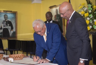 Governor-General, His Excellency the Most Hon. Sir Patrick Allen (right), looks on as Minister of Justice, Hon. Delroy Chuck, signs the Instrument of Appointment during Wednesday’s (September 17) Swearing-in Ceremony for Cabinet Members at King’s House.

