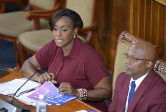 Speaker of the House of Representatives, the Most Hon. Juliet Holness, addresses the Opening Ceremony for the Orientation of Members of Parliament (MPs) at Gordon House in downtown Kingston on Tuesday (September 30). Listening attentively is Chief Hansard Reporter in the Houses of Parliament, Carl Bryan.