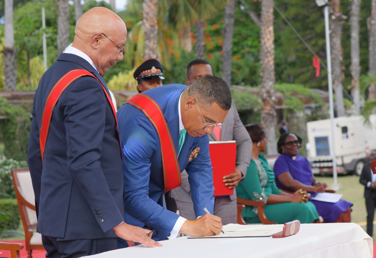 Prime Minister, Dr. the Most Hon. Andrew Holness (right), signs the Instrument of Appointment during the swearing-in ceremony at King’s House on September 16. Guiding the process is Governor-General, His Excellency, the Most Hon. Sir Patrick Allen.

