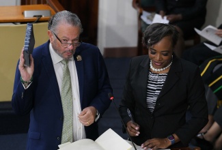 President of the Senate, Senator the Hon. Thomas Tavares-Finson, takes the Oath of Allegiance during the swearing-in of members of the Upper House at Gordon House on September 18. Observing the proceeding is Clerk to the Houses of Parliament, Colleen Lowe.

