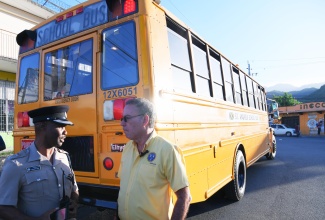 Science, Energy, Telecommunications and Transport Minister, Hon. Daryl Vaz (right), is in conversation with Superintendent of Police, Jeffery Lecky, in Papine Square on Monday (September 8). The Minister was observing the rollout of the National Rural School Bus Programme.

