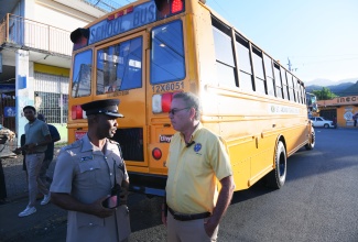 Science, Energy, Telecommunications and Transport Minister, Hon. Daryl Vaz (right), converses with Superintendent of Police, Jeffery Lecky, in Papine, St. Andrew, on Monday (September 8), while observing the rollout of the National Rural School Bus Programme.