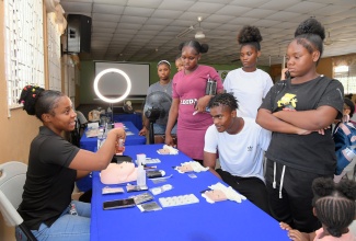 A group of workshop participants gather as lash extension instructor, Calaya Edwards (left), explains the various steps of the trade at the Social Development Commission’s (SDC) second annual Youth Entrepreneurship Skills Symposium (YESS), held on Friday (August 29) at the Worldwide Church of God in Christian Gardens, Portmore, St. Catherine. During the workshop, participants received training in welding, candle-making, bouquet and gift basket creation, lash extension techniques and photography.
