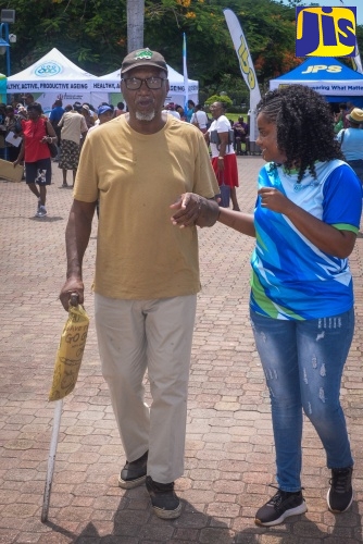 Records and Information Management (RIM) Officer at the National Council for Senior Citizens (NCSC), Nesa Lawrence (right), assists visually impaired senior citizen, Karl Morrison, during an Ageing Fair held at Emancipation Park in St. Andrew on Thursday (Sept. 11).