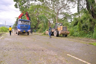 Workmen from the National Solid Waste Management Authority (NSWMA) use heavy equipment to clear a section of the Mandela Highway at the Portmore intersection on Wednesday (October 29). Fallen trees and other debris from the passage of hurricane Melissa, left the westbound section of the Highway, towards Spanish Town, impassable.