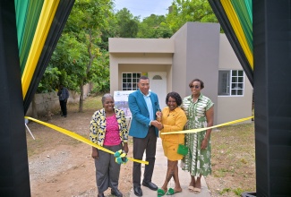 Prime Minister, Dr. the Most Hon. Andrew Holness (second left) and New Social Housing Programme (NSHP) recipient, Denique Groves (second right), cut the ribbon for her new home in Shooters Hill, Bull Bay, St. Andrew, on October 15. Sharing in the moment are Member of Parliament for St. Andrew East Rural, the Most Hon. Juliet Holness (right), and Chair of the NSHP, Judith Robb-Walters.

