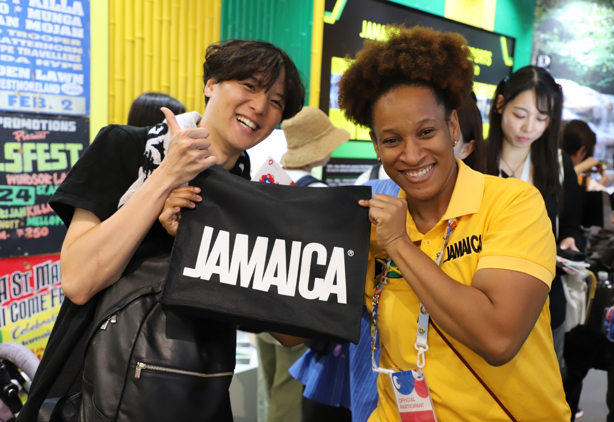 Volunteer at the Jamaica Pavilion at Expo 2025 Osaka, Kansai, Japan, Lacy-Ann Dobson (right), presents a Jamaica T-shirt to a guest who visited the Pavilion during the final day of the Expo on October 13.

