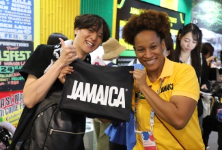 Volunteer at the Jamaica Pavilion at Expo 2025 Osaka, Kansai, Japan, Lacy-Ann Dobson (right), presents a Jamaica T-shirt to a guest who visited the Pavilion during the final day of the Expo on October 13.

