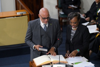 Senator Keith Duncan takes the Oath of Allegiance, during the swearing-in of members of the Upper House at Gordon House as Clerk to the Houses of Parliament, Colleen Lowe, looks on.

