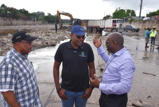 Minister without Portfolio in the Ministry of Economic Growth and Infrastructure Development with Responsibility for Works, Hon. Robert Morgan (centre); Member of Parliament for St. Andrew Western, Hon. Anthony Hylton (left); and Communication and Customer Services Manager at the National Works Agency (NWA), Stephen Shaw, engage in discussion while standing in the Sandy Gully, where desilting activities were under way. The officials visited the site on Wednesday (October 22) to observe the ongoing flood mitigation works being spearheaded by the NWA in preparation for the anticipated impact of Tropical Storm Melissa, expected to affect Jamaica within 48 hours.