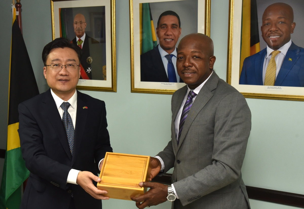 Minister of Labour and Social Security, Hon. Pearnel Charles Jr. (right), receives a gift from Ambassador of the People’s Republic of China to Jamaica, His Excellency Wang Jinfeng, during a courtesy call at the Ministry's North Street offices on Thursday (October 9).