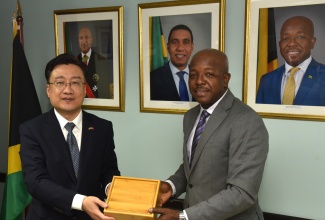 Minister of Labour and Social Security, Hon. Pearnel Charles Jr. (right), receives a gift from Ambassador of the People’s Republic of China to Jamaica, His Excellency Wang Jinfeng, during a courtesy call at the Ministry's North Street offices on Thursday (October 9).