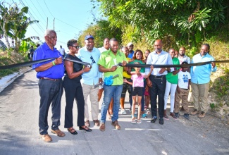 Minister of Agriculture, Fisheries and Mining, Hon. Floyd Green (fourth left), cuts the ribbon to officially open the Mount Olive Farm Road in St. Andrew recently. Joining him (from left) are State Minister in the Ministry, Hon. Franklin Witter; Member of Parliament for West Rural St. Andrew and State Minister in the Ministry of National Security and Peace, Hon. Juliet Cuthbert-Flynn; Councillor for the Lawrence Tavern Division, John Myers; Chief Executive Officer of the Rural Agricultural Development Authority (RADA), Garnet Edmondson and other members of the community.