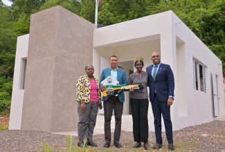 Prime Minister, Dr. the Most Hon. Andrew Holness (second left) presents New Social Housing Programme (NSHP) recipient Gloria Williams (second right) with a symbolic key during the handover of her new home in Red Hills, St. Andrew, on October 15. Sharing in the moment are Member of Parliament for St. Andrew North Central, Hon. Delano Seiveright (right), and Chair of NSHP, Judith Robb-Walters.

