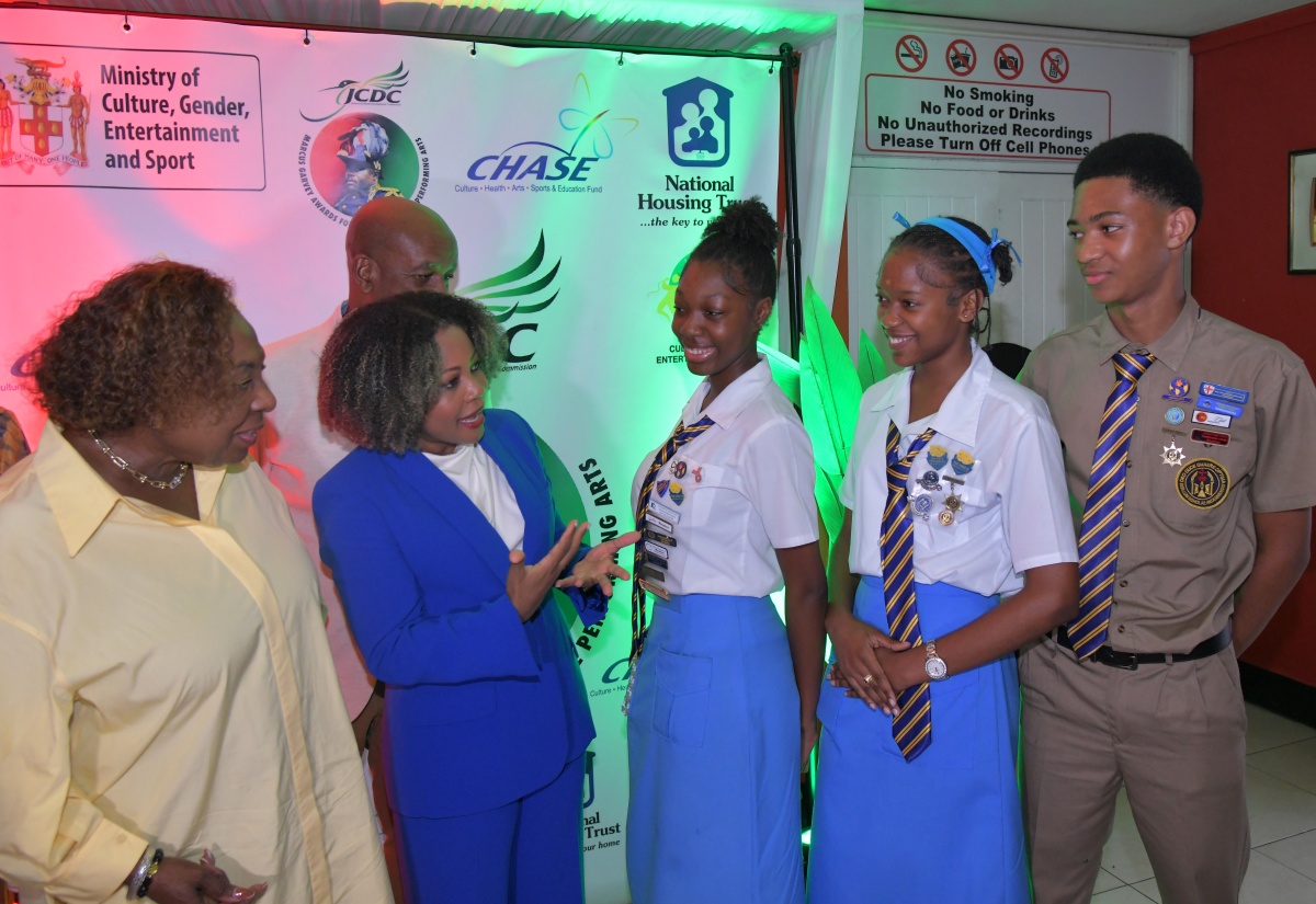 Minister of Culture, Gender, Entertainment and Sport, Hon. Olivia Grange (left), and Minister of Education, Skills, Youth and Information, Senator Dr. the Hon. Dana Morris Dixon, interact with Ardenne High School students (from third left) Arhiyanna Kentish, Rihanna Henry and Azzuri West at the 31st staging of the Jamaica Cultural Development Commission (JCDC) Marcus Garvey Awards for Excellence in the Performing Arts, held at the Little Theatre on October 15. In the background is Executive Director of the JCDC, Lenford Salmon.