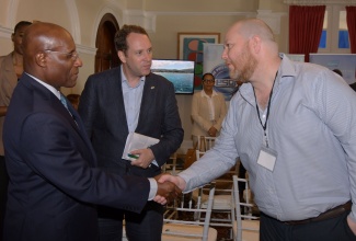 Minister of Industry, Investment and Commerce, Senator the Hon. Aubyn Hill (left), greets Business Development Director, Mowlem International Limited, Adrian Wilson, during Wednesday’s (October 8) business briefing and press engagement for the United Kingdom (UK) Trade Mission to Jamaica 2025 at the British High Commission in New Kingston. At centre is Deputy British High Commissioner to Jamaica, Jonathan Cook.

