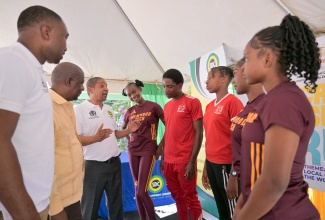 Minister of State in the Ministry of Local Government and Community Development, Hon. Delroy Williams (third left), speaks to runners before they set off on the first leg of the annual Cross-Island Run, being held under the theme ‘Local Government: The Work Continues’, on October 21 in Mandeville. Others (from left) are Executive Director of the Social Development Commission, Omar Frith, and Mayor of Mandeville, His Worship Councillor Donovan Mitchell.
