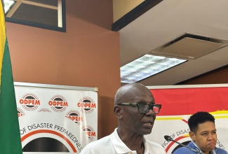 Minister of Local Government and Community Development, Hon. Desmond McKenzie addressing a press briefing at the National Emergency Operations Centre (NEOC) at the Office of Disaster Preparedness and Emergency Management in Kingston on October 28. At right is Sign Language and Spoken English Interpreter, Antoinette Aiken.