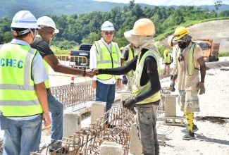 Minister without Portfolio in the Ministry of Economic Growth and Infrastructure Development with responsibility for Works, Hon. Robert Morgan (second left), greets Montego Bay Perimeter Road workers in St. James during a tour of the project on Wednesday (October 15). Looking on is Project Manager at China Harbour Engineering Company (CHEC), Hongsheng Gui (third left). 