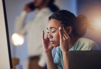 Tired employee with a headache working late in the office, showing signs of fatigue and stress.