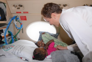 Minister of Foreign Affairs and Foreign Trade, Senator the Hon. Kamina Johnson Smith, shares a moment with conjoined twins, Azora and Azaria Elson, aboard an aircraft at Norman Manley International Airport in Kingston on July 27, ahead of their departure to the Kingdom of Saudi Arabia for separation surgery.

