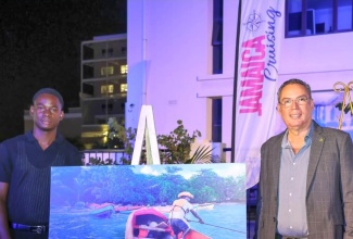 Minister of Energy, Transport and Telecommunications, Hon. Daryl Vaz (right), and winner of the Maritime Authority of Jamaica (MAJ) High school Photo Competition, Matthew-Rae Edmondson, are photographed with the winning picture.

