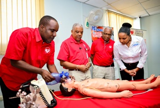 Heart Foundation of Jamaica (HFJ) Training Manager, Alonzo Mothersill (left), demonstrates an emergency procedure on a child mega code, during Wednesday’s (November 26) handover of equipment donated by CHASE Fund at the HFJ