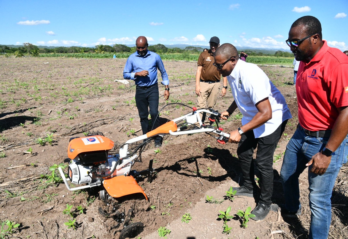 Minister of Agriculture, Fisheries and Mining, Hon. Floyd Green (second right), demonstrates how a walk-behind tractor can be used in ploughing land. The demonstration exercise followed a handover ceremony for walk-behind tractors and earth augers, held on Wednesday (November 26) at the Amity Hall Agro-Park in St. Catherine. The equipment will be distributed in parishes with difficult terrain that were not hard hit by Hurricane Melissa, to assist with the Ministry’s recovery strategy. Observing (from left) are Rural Agricultural Development Authority (RADA) Chief Executive Officer (CEO), Garnet Edmondson, CEO of Agri-Invest Corporation (AIC), Vivion Scully and Agriculture Landscaping and Distribution Manager at Delta Supply Company Limited, Vengsarka Grant.

