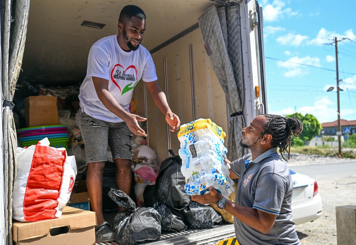 Businessman, Garrie “Wanda Oh Canada” Parker (right), hands a case of water to colleague Christopher Davy as the first box truck is loaded with relief supplies for Hurricane Melissa victims in western Jamaica under the “St. Thomas Helping Hands” initiative on Thursday (November 6).

