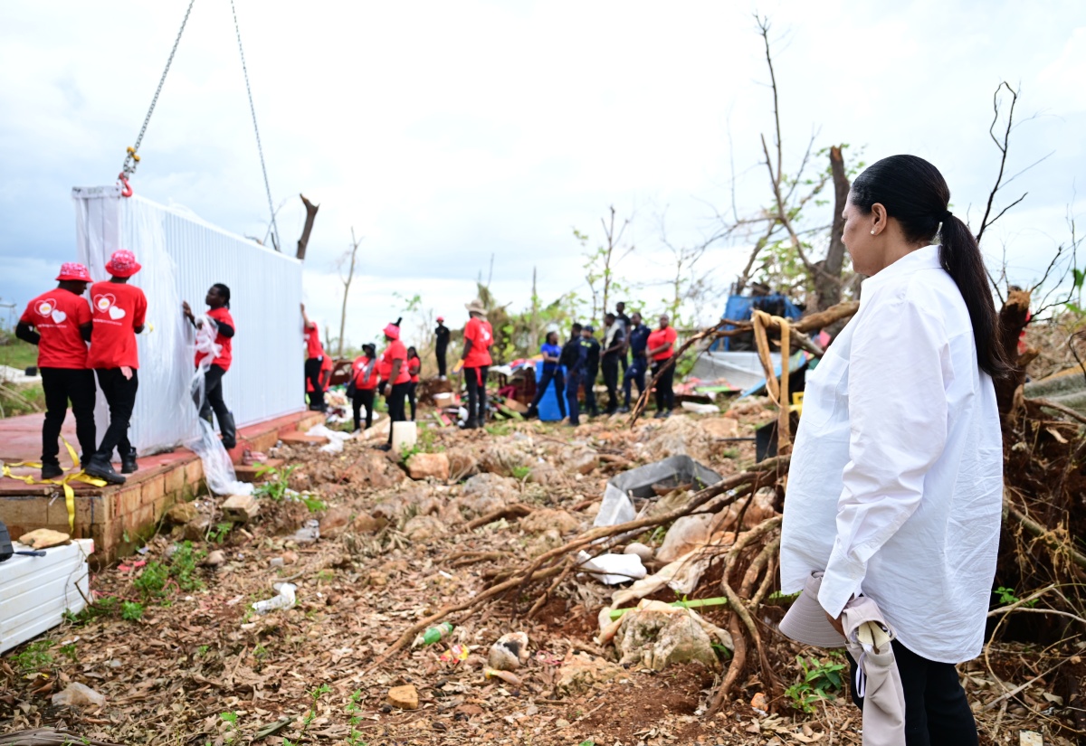 Custos of Clarendon, Hon. Edith Chin (right), looks on while volunteers from Juici Patties set up a prefabricated house for a mother of six children, in the community of Middle Quarters, St. Elizabeth, on November 13. The donation was done through her Hurricane Melissa Relief Mission.

