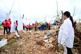 Custos of Clarendon, Hon. Edith Chin (right), looks on while volunteers from Juici Patties set up a prefabricated house for a mother of six children, in the community of Middle Quarters, St. Elizabeth, on November 13. The donation was done through her Hurricane Melissa Relief Mission.

