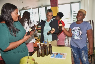 Minister of State in the Ministry of Culture, Gender, Entertainment and Sport, Hon. Kerensia Morrison (left), examines a bottle of honey produced by St. Ann farmer Merissa Reider (right), alongside Representative of the Jamaica Network of Rural Women Producers (JNRWP), Susanne Uter (centre). They were at the International Day of Rural Women (IDRW) 2025 Empowerment Forum and “FarmHers” Market held in October, at the Ministry’s Kingston office, under the theme ‘She Invests: Turning Challenges into Opportunities’.

