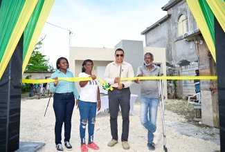 Prime Minister, Dr. the Most Hon. Andrew Holness (second right), cuts the ribbon to officially hand over a New Social Housing Programme (NSHP) unit to beneficiary, Beverly Barnaby Moo-Young (second left), in Savanna-La-Mar, Westmoreland on Friday ( November 28). Also sharing in the occasion are (from left) Permanent Secretary in the Ministry of Economic Growth and Infrastructure Development, Arlene Williams, and Mrs. Barnaby Moo-Young’s husband, Antoney Moo-Young.