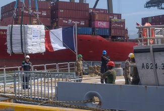 Crew members offload relief items from an overseas assistance vessel at the Kingston Freeport Terminal Limited (KFTL) in Kingston, on Monday (November 3).