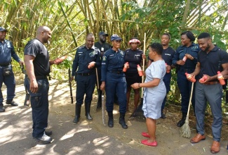 Principal of the Guanaboa Vale Primary School in St. Catherine, Tracey-Ann Brown (centre), serves bottled drinks to officers of the Guanaboa Vale Police Station, today (November 3), during a workday to clear debris from the roadway, caused by Hurricane Melissa.