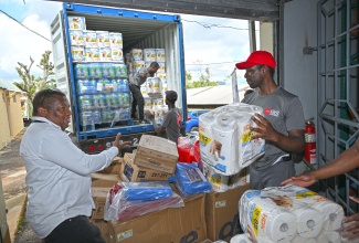 Regional Director at the Southern Regional Health Authority (SRHA), Michael Bent (left) views hurricane relief supplies dated by the AIDS Healthcare Foundation (AHF), at a handover ceremony, held yesterday (November 7), at the Grey Ground Small Industrial Complex, in Manchester.