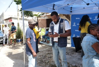 Chief Executive Officer of the Universal Service Fund (USF), Charlton McFarlane (right), assists resident of Montpelier, Hanover, Lloyd Stewart (left), in accessing Starlink Wi-Fi service via a mobile unit deployed in the community on November 7.


