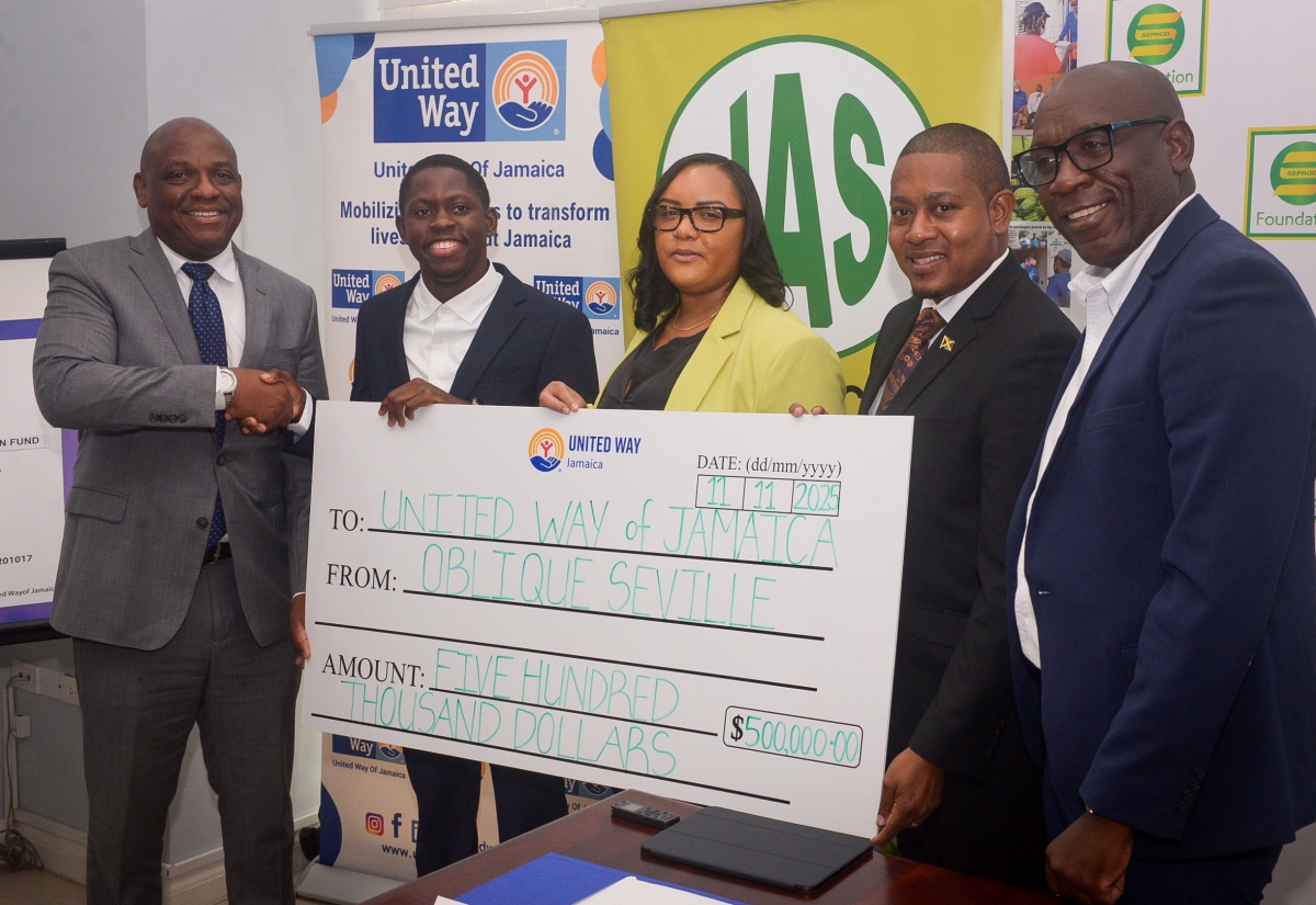 Minister of Agriculture, Fisheries and Mining, Hon. Floyd Green (second right), joins in the handover of a cheque valued at $500,000 to the United Way of Jamaica’s Restoration and Rehabilitation Fund by Jamaica’s 100-metre World Champion, Oblique Seville (second left). The presentation was made at a press conference to officially launch the fund on Tuesday (November 11), at the offices of the Private Sector of Jamaica in St. Andrew.  Sharing in the moment (from left) are Chair of the Board of Governors, United Way of Jamaica (UWJ), Dr. Devon Smith; Officer in Charge, UWJ, Kerry-Lee Lynch; and Chief Executive Officer, Jamaica Agricultural Society (JAS), Derron Grant. 


