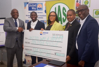 Minister of Agriculture, Fisheries and Mining, Hon. Floyd Green (second right), joins in the handover of a cheque valued at $500,000 to the United Way of Jamaica’s Restoration and Rehabilitation Fund by Jamaica’s 100-metre World Champion, Oblique Seville (second left). The presentation was made at a press conference to officially launch the fund on Tuesday (November 11), at the offices of the Private Sector of Jamaica in St. Andrew.  Sharing in the moment (from left) are Chair of the Board of Governors, United Way of Jamaica (UWJ), Dr. Devon Smith; Officer in Charge, UWJ, Kerry-Lee Lynch; and Chief Executive Officer, Jamaica Agricultural Society (JAS), Derron Grant. 

